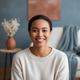Portrait of a smiling woman in her late 20s, looking at the camera with a happy, trustworthy expression. Background is softly